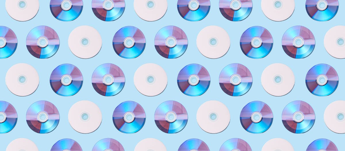 Colorful CDs arranged in a geometric pattern on a light blue background, creating a vibrant visual.