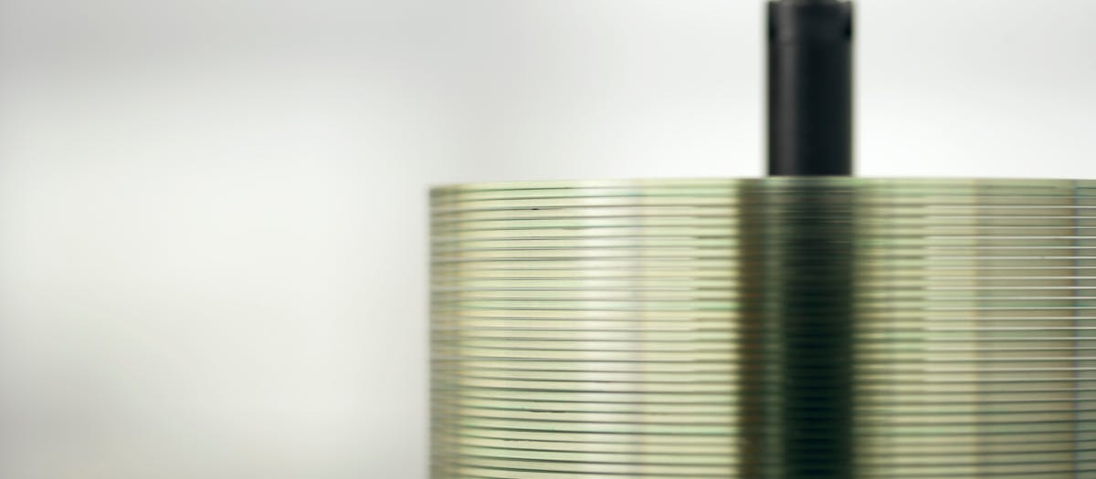 Detailed view of a stack of compact discs on a spindle, highlighting their reflective surfaces.