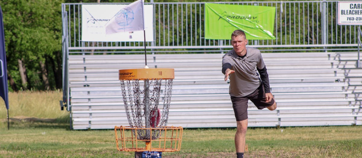 A man throws a disc towards the basket during a disc golf tournament in Clearwater, MN.